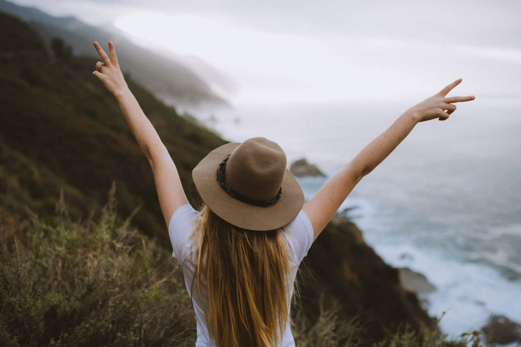 Girl holding peace sign on big sur california coast