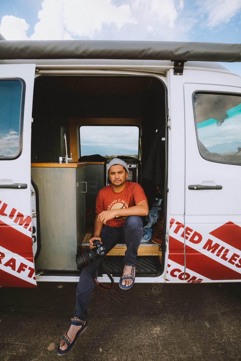 Berty sitting on side of sprinter van while camping