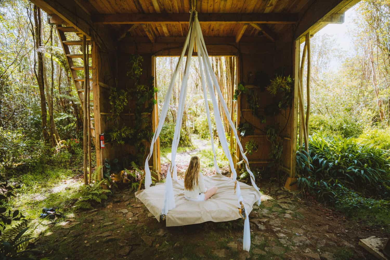 Emily sitting on swinging bed in Hawaii Treehouse - TheMandagies.com