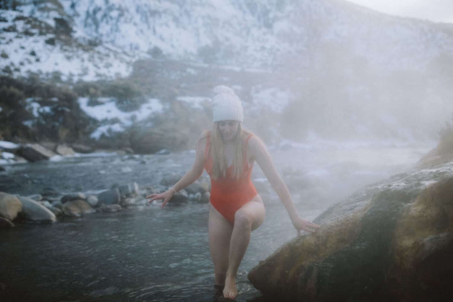 Emily Mandagie in red swimsuit in the Boiling River Yellowstone - TheMandagies.com
