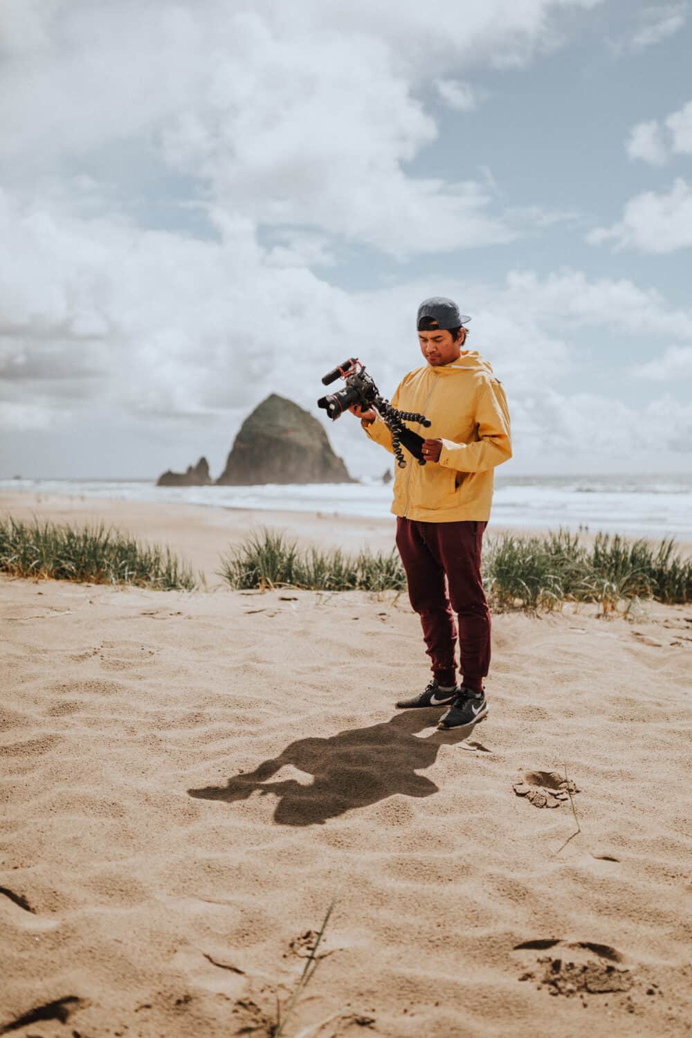 An image capturing the scenic beauty of Cannon Beach, Oregon, featuring its iconic Haystack Rock against a backdrop of sandy shorelines and rolling waves. Visitors stroll along the beach, enjoying the breathtaking coastal scenery and clear blue skies.