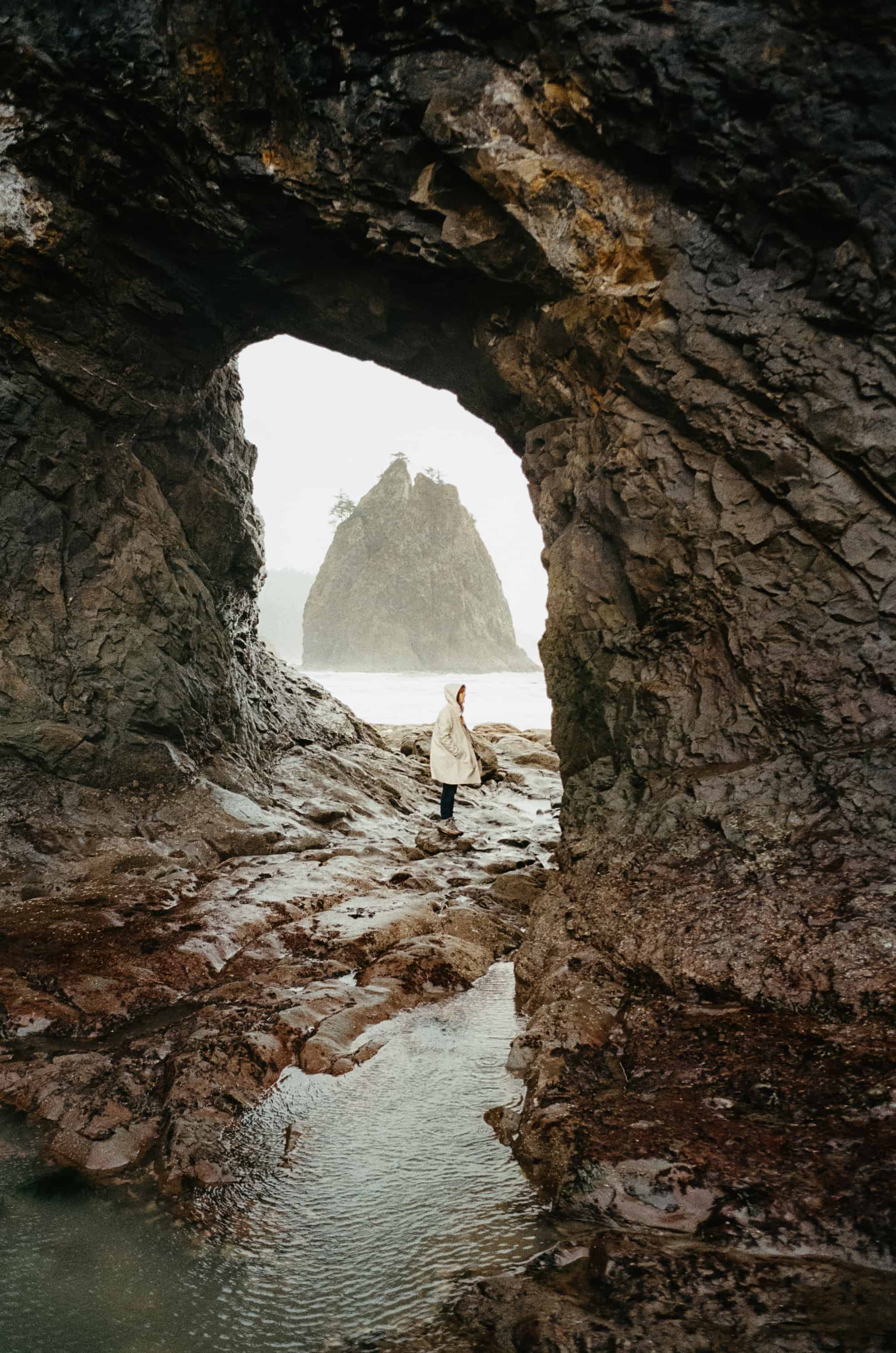 Emily Mandagie standing in Hole In The Wall, Rialto Beach WINTER SEASON - TheMandagies.com