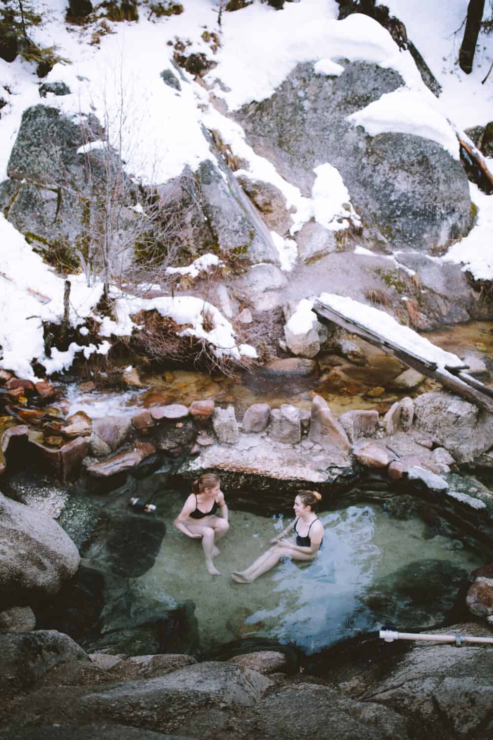 Emily Miller and Emily Mandagie sitting in Trail Creek Hot Springs soaking pools