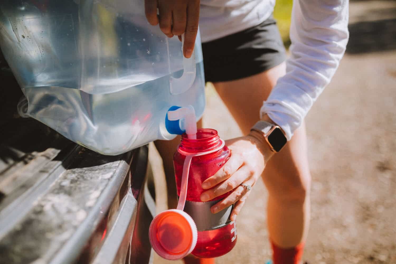 Filling up a water bottle from a large water container