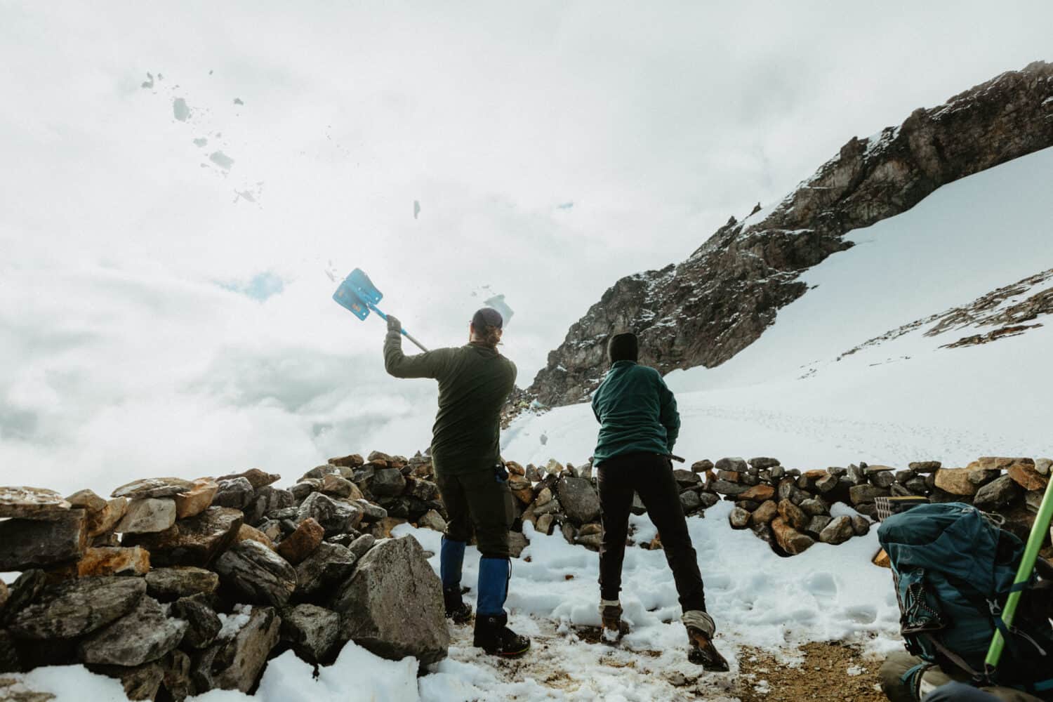 Shoveling snow out of the rock ring structures at Sahale Glacier Camp