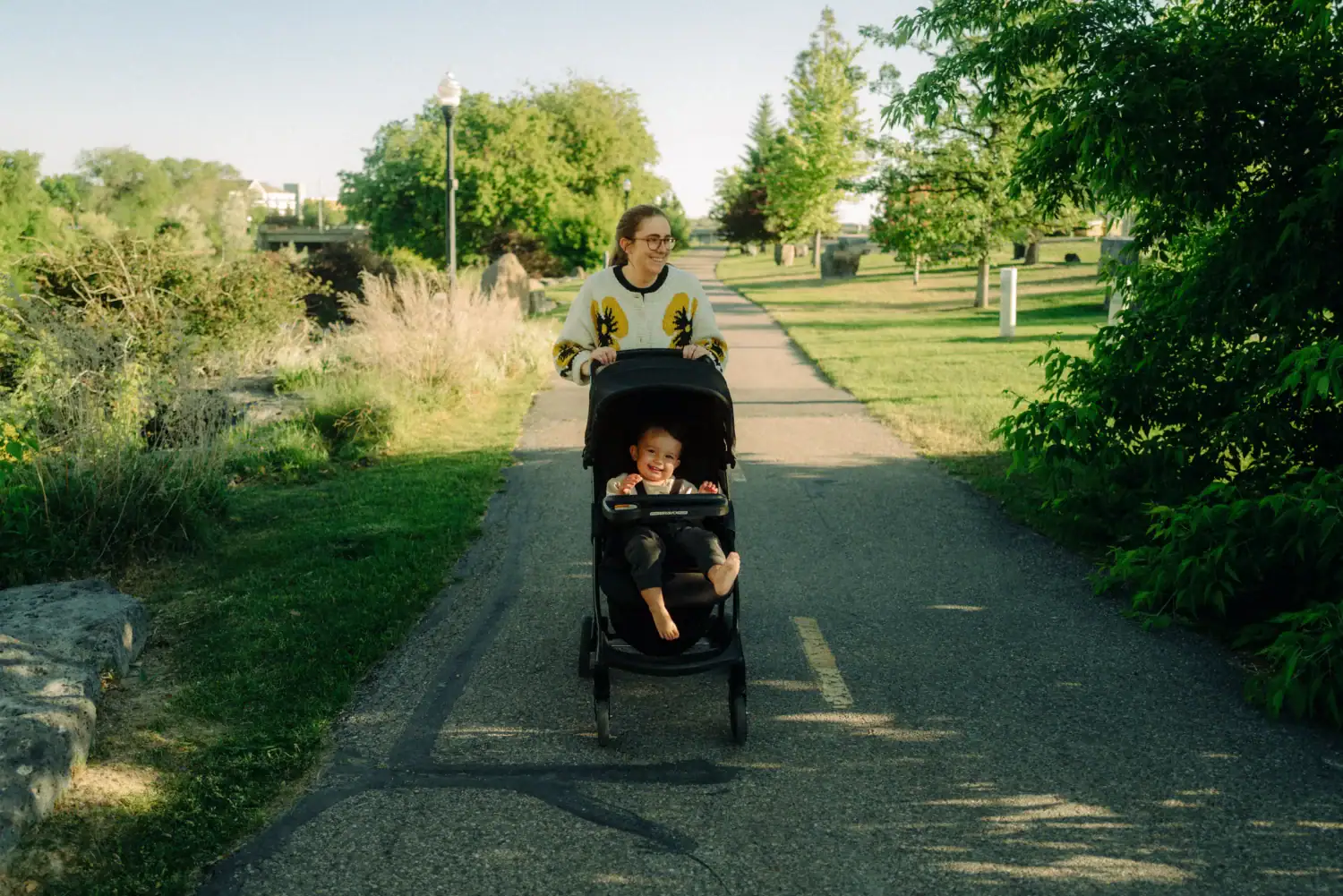 Emily Mandagie pushing a stroller along the Snake River Greenbelt path in Idaho Falls with a toddler
